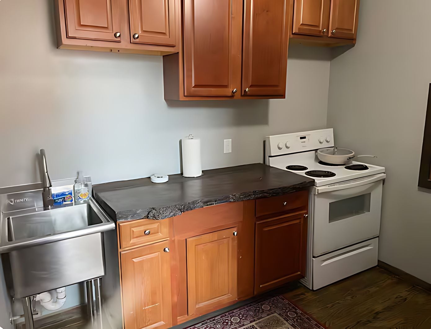 Una cocina con armarios de madera, un lavamanos de acero inoxidable y una estufa blanca.