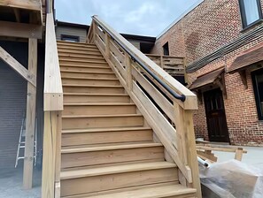 Una escalera de madera con barandilla de metal que conduce a la entrada de un edificio.