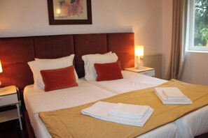 A hotel room with two beds, a headboard, bedside lamps, and a window with curtains. - QUINTA DAS GERAIS (Marco de Canaveses)