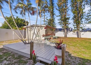 Eine Terrasse mit Holzdeck, Gartenmöbeln und einem kleinen Tisch.