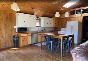 A compact kitchen with wooden cabinets, a microwave, a sink, and a refrigerator. - Remote River Retreat, Kayak, Fish, Canoe & More (Augusta)