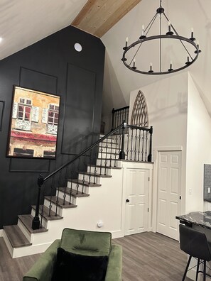 Eine Treppe mit schmiedeeisernem Geländer führt zu einem Zwischenpodest mit einer weißen Tür.