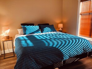 Une chambre à coucher avec un lit, deux lampes de chevet et une fenêtre avec des stores.