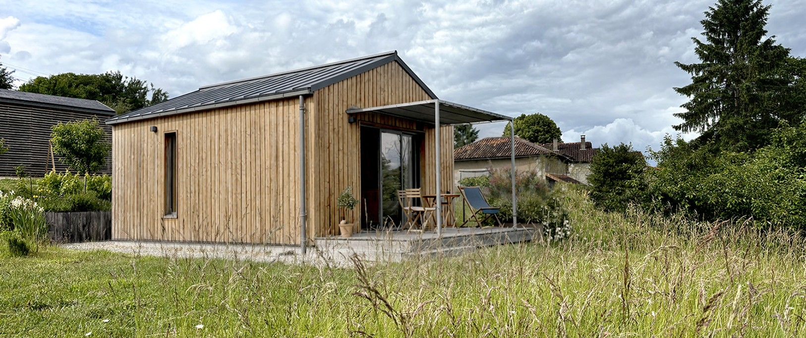 Une cabane en bois dotée d’un porche abrité et d’un petit jardin.
