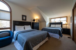 Une chambre avec deux lits, une table de chevet, une chaise et un tableau au mur.