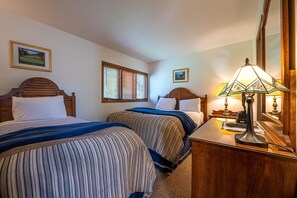 Une chambre d’hôtel avec deux lits, une table de chevet, une lampe et un miroir.