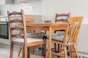 Een houten eettafel met vier stoelen, elk met een bekleed zitvlak en rugleuning.