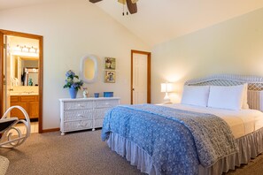 Une chambre à coucher avec un lit, une commode, un miroir et des œuvres d’art murales.