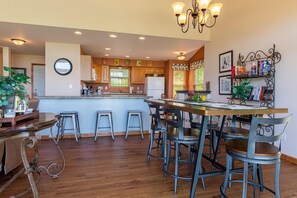 Une cuisine spacieuse avec des meubles en bois, un îlot central doté de tabourets et un coin repas avec une longue table et des chaises.