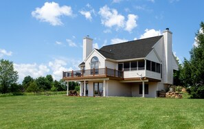 Une maison à deux étages avec un balcon, de grandes fenêtres et une cheminée.