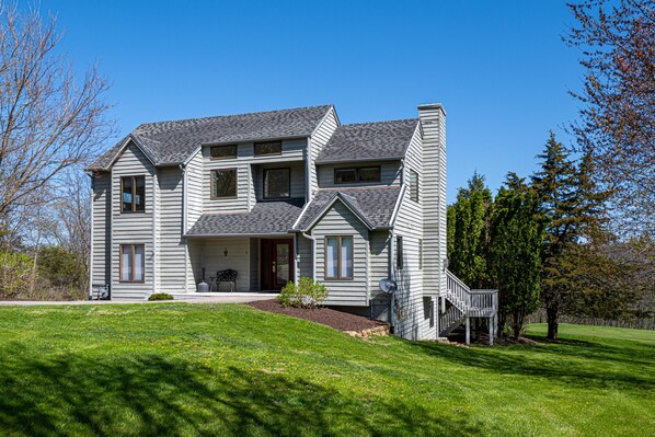 Une maison à deux étages avec un porche à l’avant, un hall d’entrée couvert et un petit jardin devant la maison.