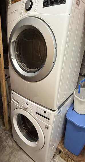 A stacked washer and dryer unit with control panels and a blue trash bin nearby. - Lakefront with dock, kayaks and fire pit on Watauga Lake (Butler)