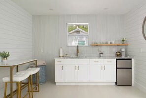 Een moderne keuken met witte kasten, een roestvrijstalen koelkast en een raam met uitzicht op groen.