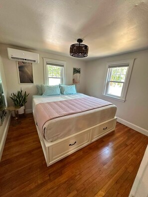A bedroom with a bed, a ceiling fan, and two windows. - 3-bedroom Cozy Cottage in perfect Marshfield with, fireplace & beach nearby. (Marshfield)