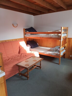 A bunk bed with a wooden frame, a red sofa, and a small table with a patterned top. - New Listing (Arette)