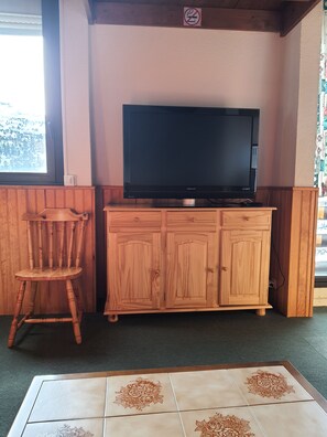 A wooden cabinet with a television on top, a wooden chair, and a tiled floor with floral patterns. - New Listing (Arette)