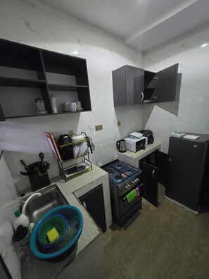 A compact kitchen with a gas stove, microwave, and a black refrigerator. - Amazing 3-bedroom apartment in peaceful Abeokuta perfect for your stay. (Abeokuta)