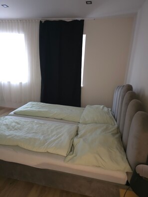 Une chambre à coucher avec un lit, une fenêtre avec des rideaux et un radiateur fixé au mur.
