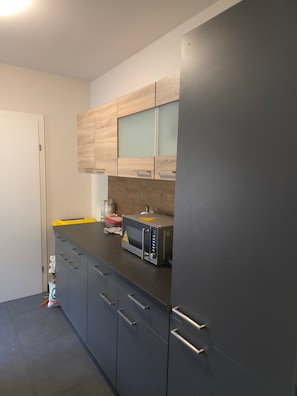 Une cuisine équipée d’un four à micro-ondes, de placards et d’une porte.