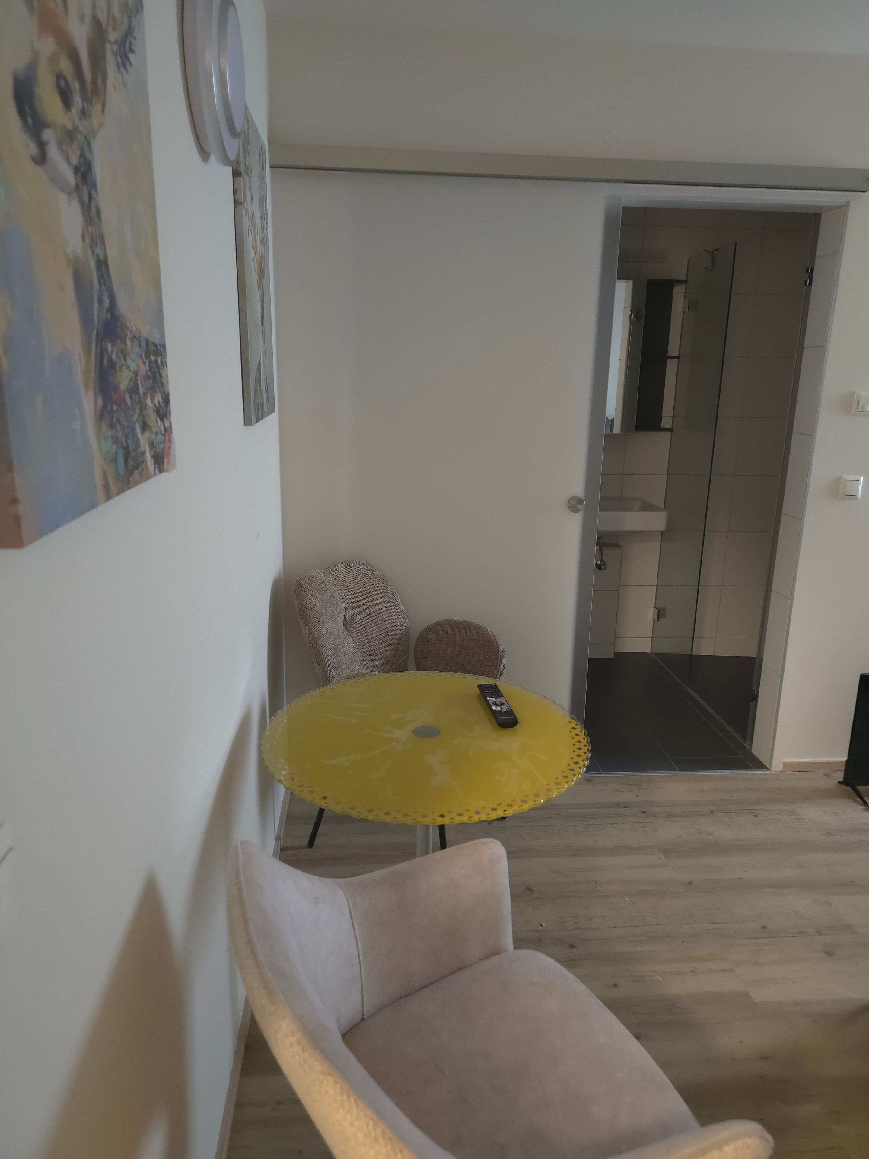Une pièce avec une table jaune, une chaise et une télécommande posée sur la table.