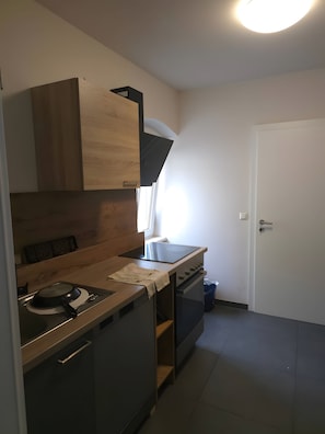 A kitchen with a stove, oven, and wooden cabinets. - Room 'Doppelzimmer Neu' with Wi-Fi (Linz)