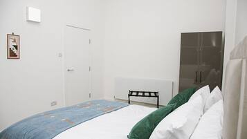 Une chambre à coucher avec un lit, un radiateur, une porte et un tableau encadré au mur.