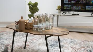Un salon moderne avec une table basse en bois, une plante en pot et un téléviseur diffusant un film.