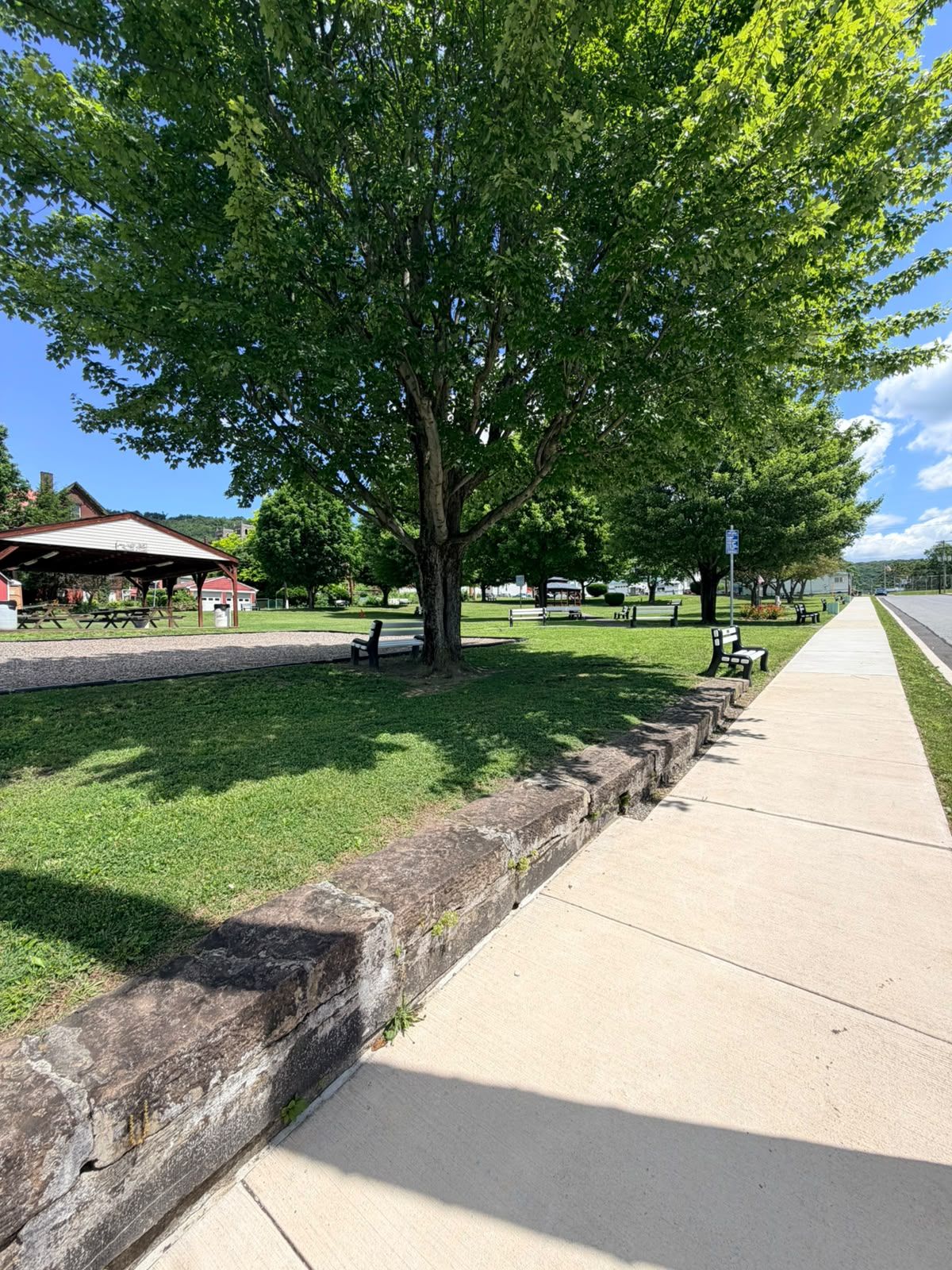 Un parque con zona de picnic, bancos y sendero para caminar.