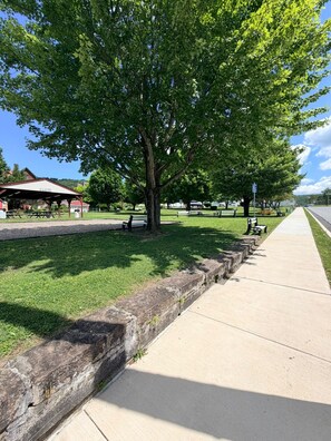 Um parque com área de piquenique, bancos e um caminho para caminhada.