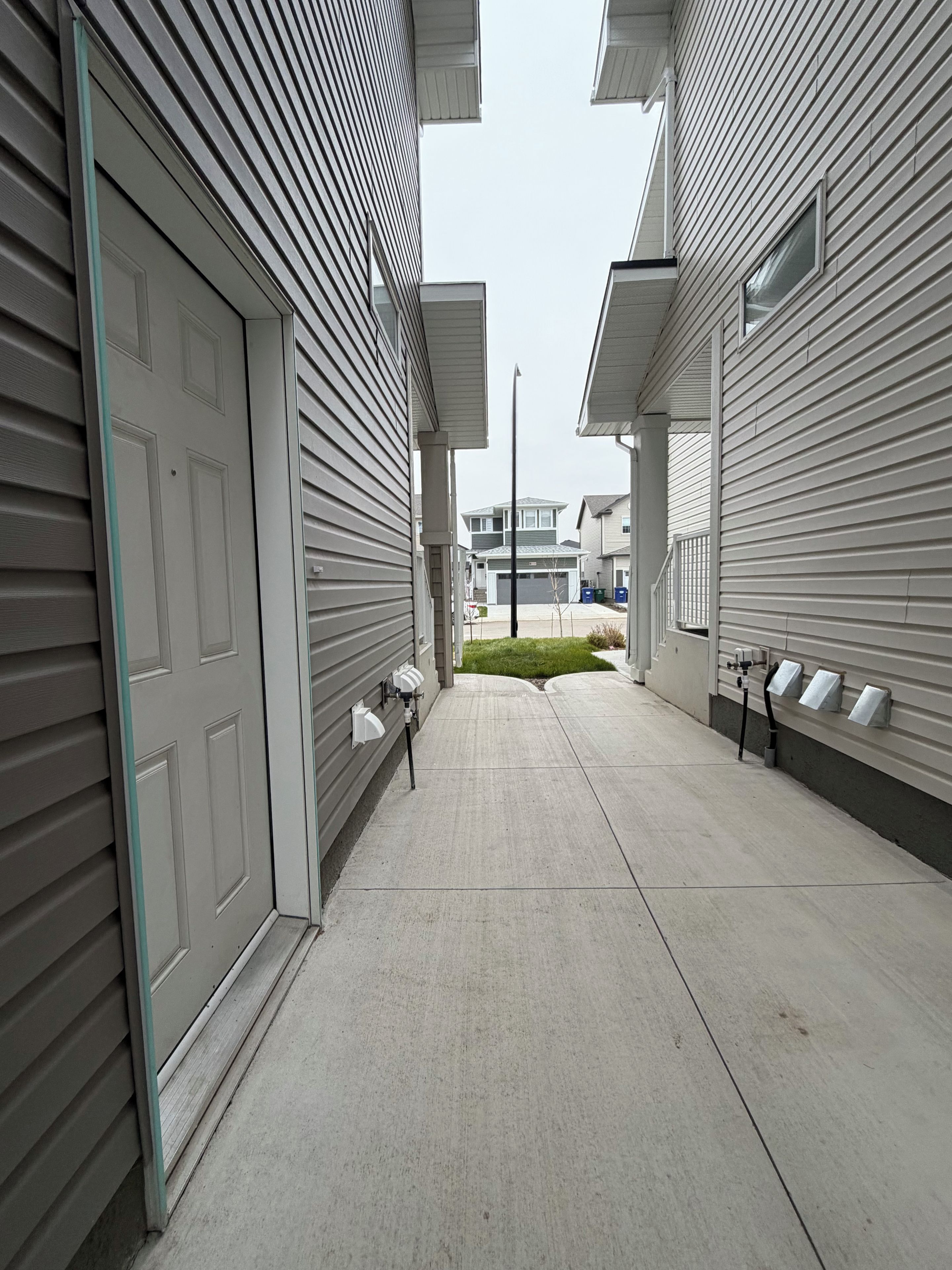 A residential street with houses, a sidewalk, and a streetlight.