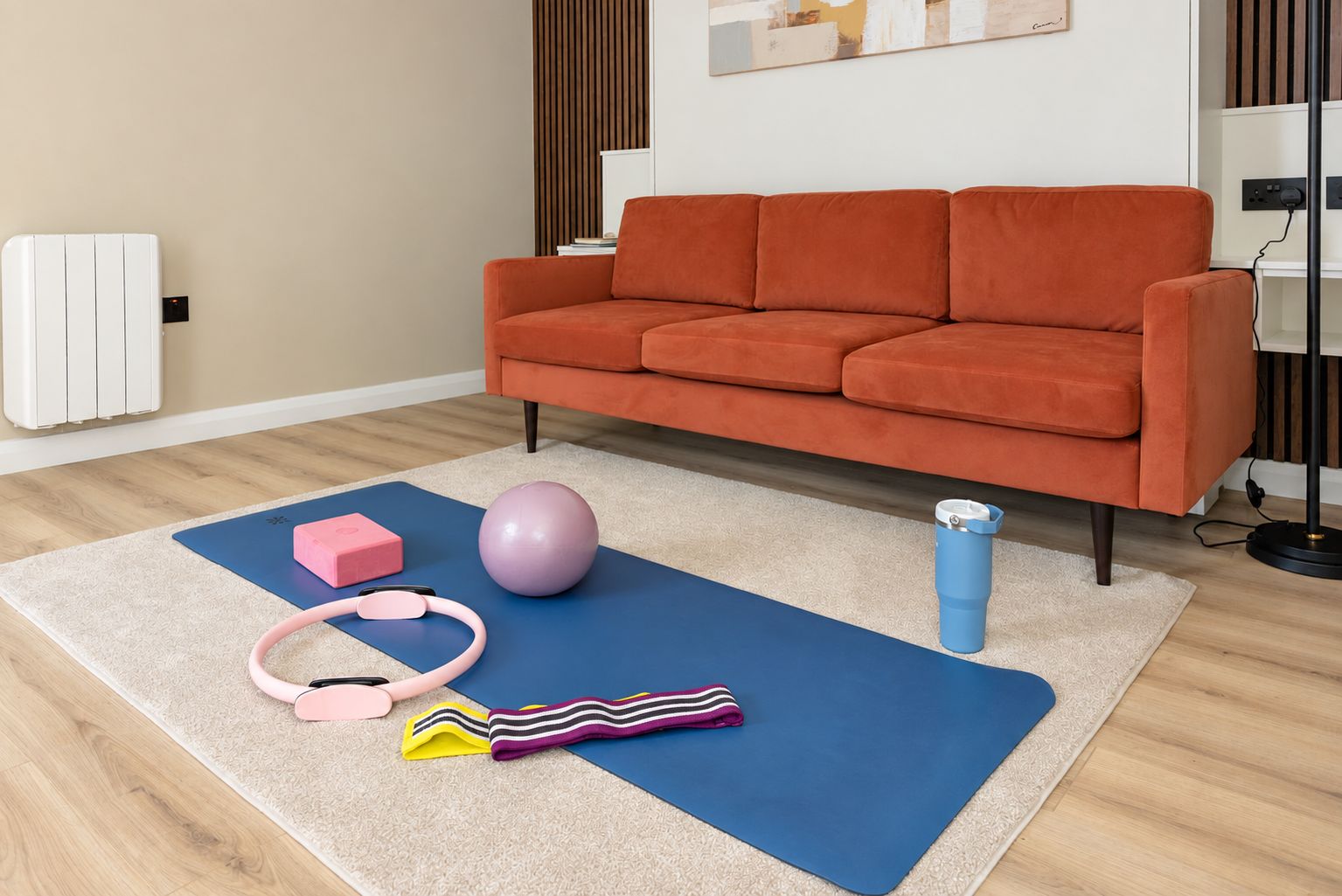 Ein Wohnzimmer mit einer Couch, einer Yogamatte, Trainingsgeräten und einer Wasserflasche.
