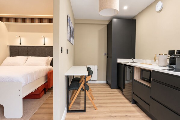 A modern bedroom with a bed, bedside table, and a small desk with a chair. - Central Westport Accessible Pet-Friendly Studio (Westport)
