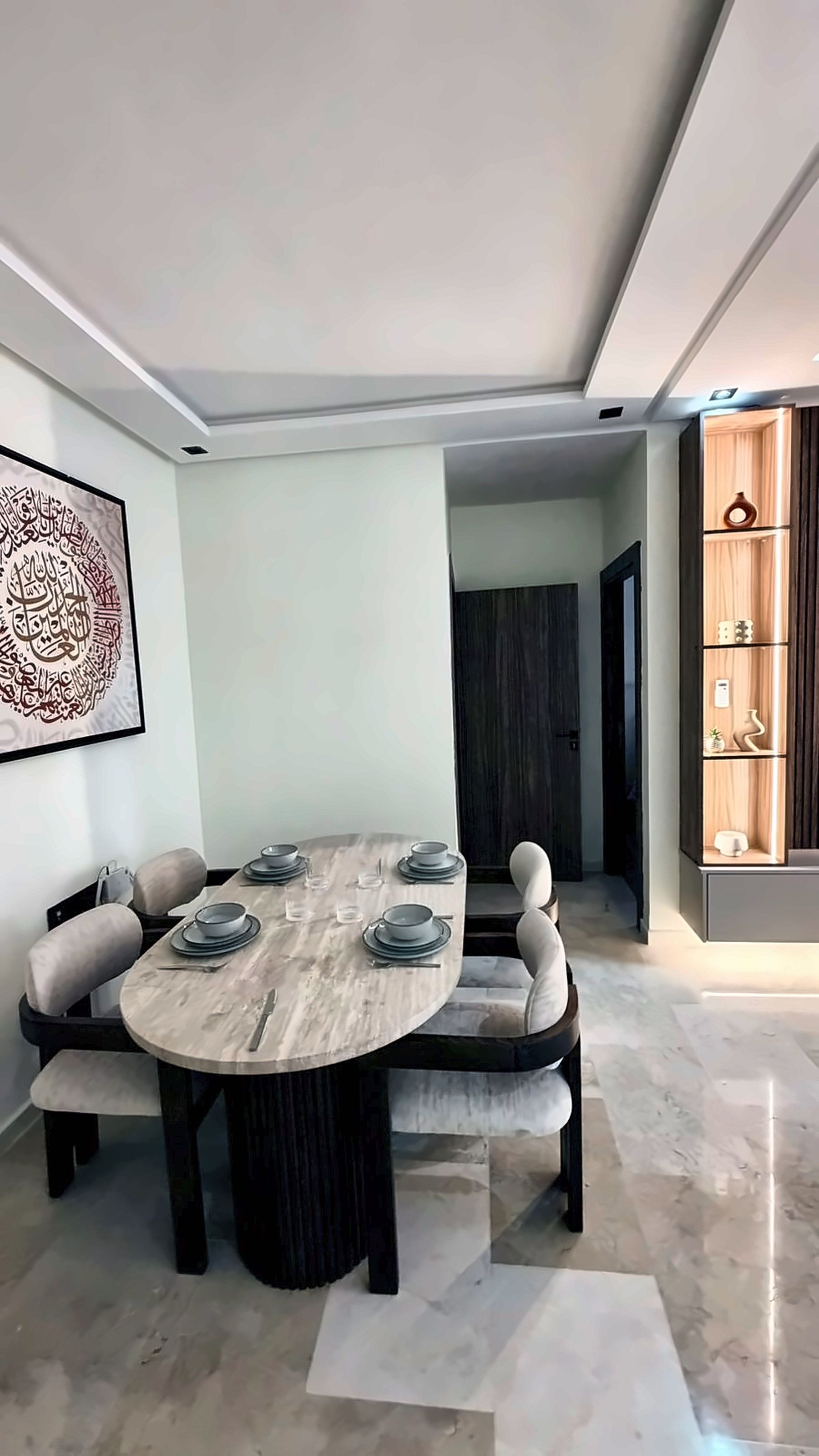 A dining area with a round table, cushioned chairs, and a decorative wall piece.
