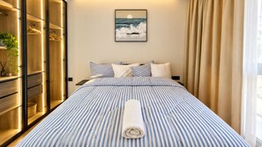 Ein Hotelzimmer mit Bett, Schrank, Nachttisch und einem Fenster mit Vorhängen.