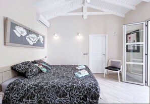 Une chambre à coucher comprenant un lit, une chaise, une porte et une œuvre d’art accrochée au mur.