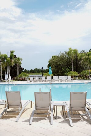Una piscina con sillones de descanso y vistas a un lago.