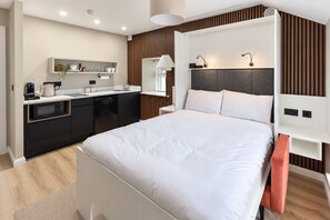 Une chambre d’hôtel moderne dotée d’un grand lit, d’un bureau intégré et d’une kitchenette.