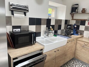 Une cuisine moderne équipée d’un four à micro-ondes, d’un four traditionnel, d’un évier et d’une machine à café, le tout placé sur une étagère.