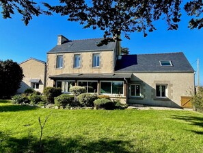 Une maison à deux étages, dotée d’un toit en pente, de grandes fenêtres et d’une pelouse bien entretenue.
