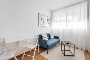 Een moderne woonkamer met een blauwe bank, een witte fauteuil en een bijzettafeltje.