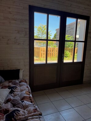 Une chambre avec un lit, une grande fenêtre et une vue sur un jardin.