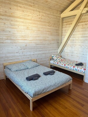 Une chambre avec deux lits en bois, l’un recouvert d’une couvre-lit et de coussins à motifs, et l’autre d’une couvre-lit et de coussins aux couleurs vives.