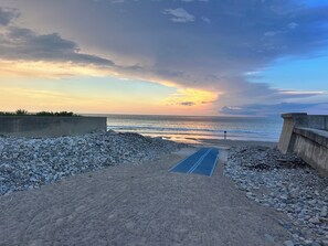 A beach with a concrete path leading to the water, surrounded by pebbles and a concrete barrier. - Nice cozy 2-bedroom guest house in charming Marshfield. Short walk to the beach. (Marshfield)