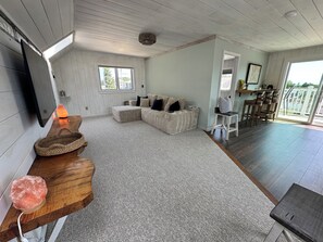 A living room with a sectional sofa, a wooden coffee table, a salt lamp, and a large window. - Nice cozy 2-bedroom guest house in charming Marshfield. Short walk to the beach. (Marshfield)