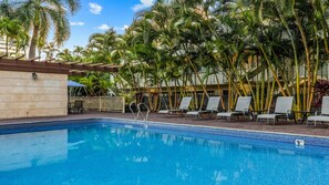 Une piscine avec des chaises longues et des palmiers.
