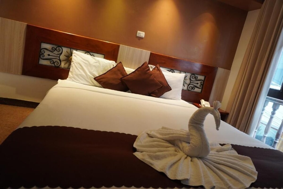 A hotel room with a bed, pillows, and a decorative swan towel.