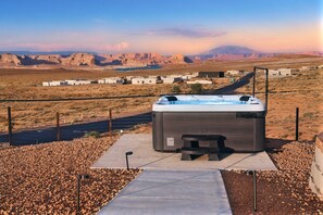 A hot tub in a desert setting with a view of a small settlement and mountains in the background. - The Red Canyon Retreat - Views, Hot Tub, Game Room (Page)