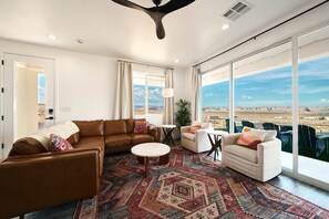 A spacious living room with a large window offering a view of a desert landscape. - The Red Canyon Retreat - Views, Hot Tub, Game Room (Page)