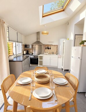 Een moderne keuken met dakraam, witte kasten en een eettafel gedekt voor vier personen.