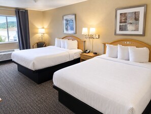 Camera d'albergo con due letti, una poltrona, una scrivania con il telefono e due lampade a parete.